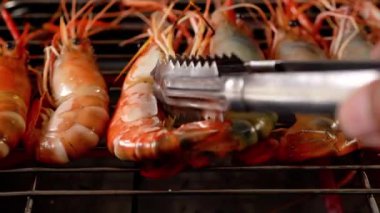 Şef elektrikli ocakta karides pişiriyor.