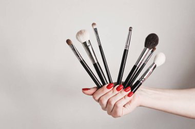 Beyaz arka planda 6 adet makyaj fırçası var. 5 'i bir arada gruplandırılmış ve resimde daha büyük bir toz fırçası ile dengelenmiştir..