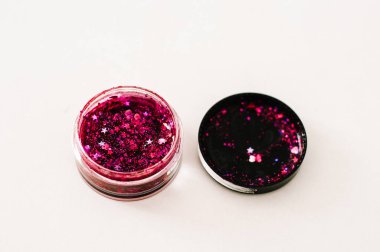 Çok renkli parıltılı küçük şişeler ve beyaz arka planda dağınık pullar.