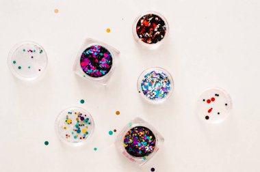 Bahşiş üzerine çivi tasarımı ve renkli bir arka planda manikür seti. Çivi dekorasyonu ve çivi tasarımı için yeşil pullar cam kavanozdan düştü..