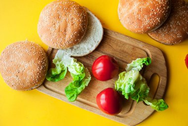 Ahşap kesme tahtasının üzerinde sebzeli sığır eti köftesi. Siyah desenli arka planda düz uzanır.