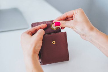 Kadın eli, pastel solmuş arka plana bozuk para koyuyor. El, açık metal bir çantanın içine hafif bir arka planda bozuk para koyar..