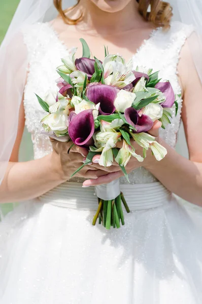 Gelin elinde güllerden, şakayıklardan ve östomadan oluşan yumuşak bir buket tutuyor.