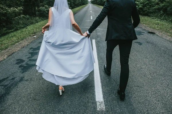 結婚式 男と女の子は石の道に行き 女の子は赤 白の花と緑の花束を持っている — ストック写真