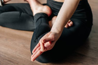 Yoga yapan genç bir kadın, öne eğik oturma egzersizi, paschimottanasana pozu spor kıyafetleri, gri pantolon, sutyen, iç mekan, iç mekan, iç mekan, iç mekan.