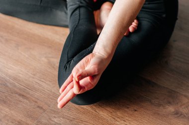 Yoga yapan genç bir kadın, öne eğik oturma egzersizi, paschimottanasana pozu spor kıyafetleri, gri pantolon, sutyen, iç mekan, iç mekan, iç mekan, iç mekan.