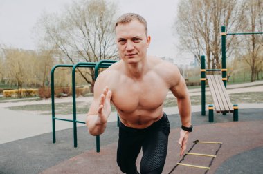 Formda sporcu stadyumda egzersiz yapıyor. Şehrin parkındaki beyaz bir genç adam. Spor egzersizlerini göster. Spor, spor, sağlık, yaşam tarzı konsepti