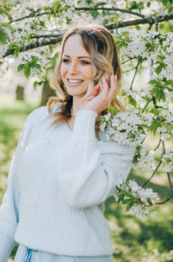 Bahar bahçesinde genç bahar moda kadını. İlkbahar. Bahar manzarasında günbatımında modaya uygun bir kız. Çiçeklerin polenine alerjisi var. Bahar alerjisi