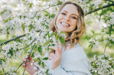 Bahar bahçesinde genç bahar moda kadını. İlkbahar. Bahar manzarasında günbatımında modaya uygun bir kız. Çiçeklerin polenine alerjisi var. Bahar alerjisi