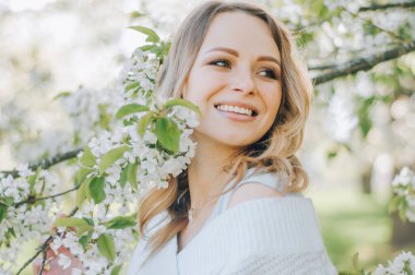 Bahar bahçesinde genç bahar moda kadını. İlkbahar. Bahar manzarasında günbatımında modaya uygun bir kız. Çiçeklerin polenine alerjisi var. Bahar alerjisi