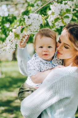 Anne ve küçük oğlu gün batımında bir yaz parkında birlikte oynuyorlar. Küçük çocuklu mutlu bir anne güneşli bir alanda eğleniyor. Öpücükler ve sarılmalar. Mutlu aile kavramı..