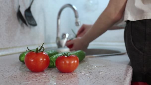 Fiatal lány mosás és öblítés zöldségek a konyhában, zárja be a vizet, és menjen el — Stock videók