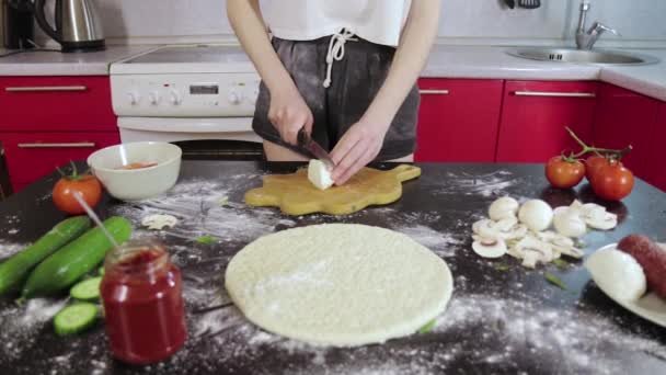 Jeune fille couper un fromage sur une planche en bois et une table noire . — Video