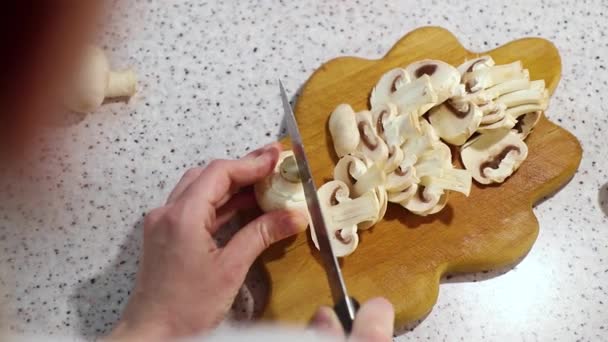 Hands of young girl cut a mushroom on the wooden cutting board, light background — Stock Video