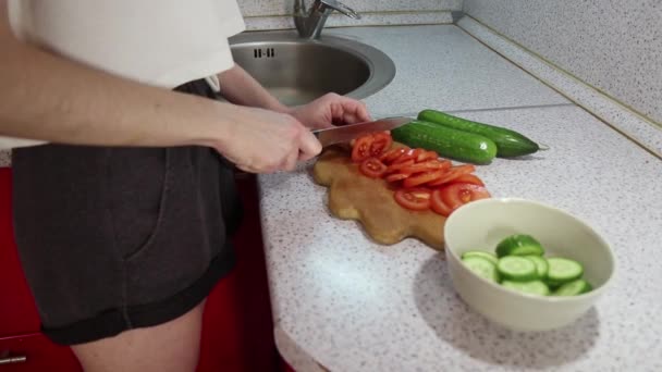 Jeune fille couper la tomate sur une planche en bois — Video