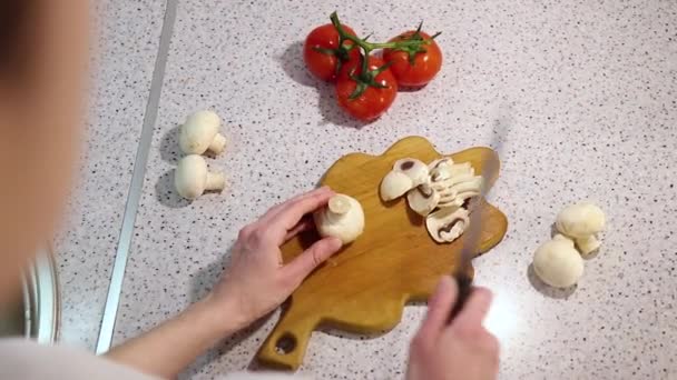 Las manos de la muchacha joven cortan la seta en la tabla de cortar de madera con los tomates — Vídeo de stock