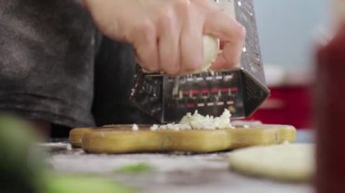 Genç bir kızın elleri, peyniri metal rendeyle iyice ovalıyor.