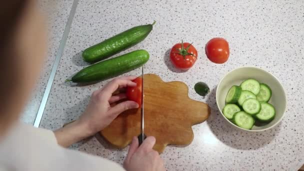 Young girl cut tomatoes and cucumbers on a wooden board — Stock Video