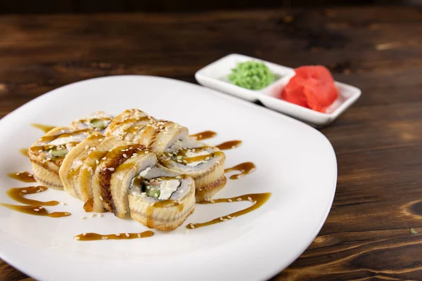 Tabakta soslu yılan balığı, bulanık arka planda wasabi ve zencefil.