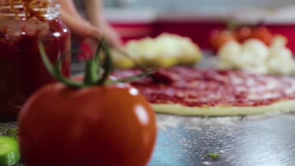 Genç kızın elleri pizza hamuruna domates ezmesi sürüyor. — Stok video