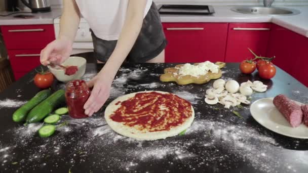 Handen van jong meisje neem tomatenpasta en smeren op pizza deeg — Stockvideo