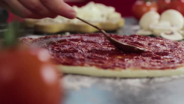 Handen van jong meisje smeren tomatenpasta op pizza deeg — Stockvideo