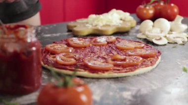 Genç kızın elleri pizza hamuruna domates koyuyor.