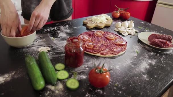 As mãos da menina põem o tomate na massa de farinha de pizza — Vídeo de Stock