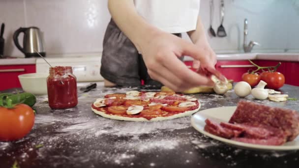 Hands of young girl put sausage on pizza dough — Stock Video