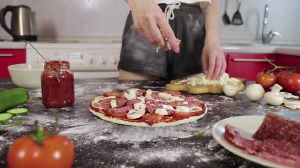 Руки молодої дівчини посипають сирним тістом для піци — стокове відео