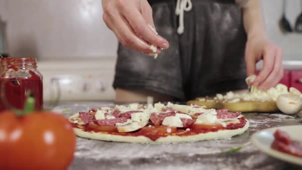 Hände eines jungen Mädchens bestreuen Käse-Pizzateig — Stockvideo