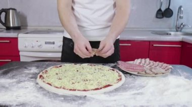 Genç adamın elleri pizza hamuruna değdi.