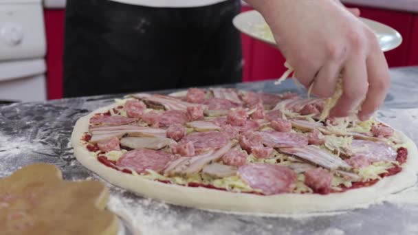 Manos de hombre espolvorear queso sobre la masa para pizza con pasta de tomate de cerca — Vídeos de Stock