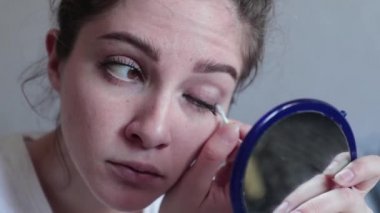 Genç kız aynaya bakarak makyaj yapıyor.