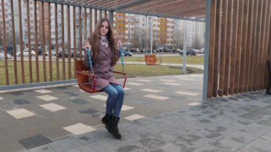 Arka planda arabalarla parkta sallanan mutlu genç kız.
