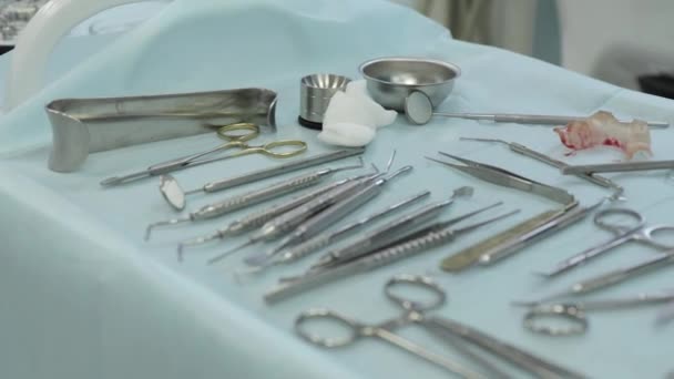 Lekarz w białych gumowych rękawiczkach kładzie narzędzie dentystyczne na stole w klinice stomatologicznej — Wideo stockowe