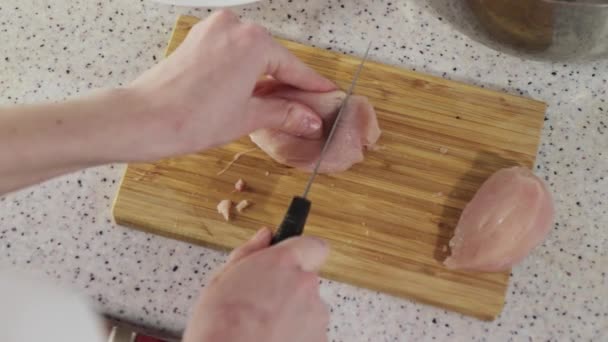 Mujer corta pechuga de pollo en la tabla de cortar de madera — Vídeos de Stock