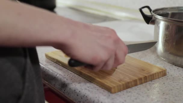 Vrouw snijdt knoflook op een houten snijplank — Stockvideo