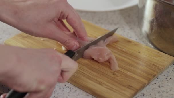 Mujer corta pechuga de pollo en la tabla de cortar de madera — Vídeo de stock