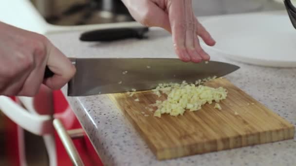 Женщина режет чеснок на деревянной доске — стоковое видео