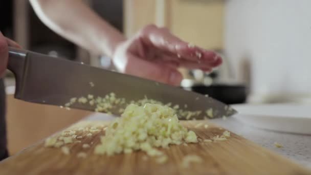 Woman chops garlic on a wooden cutting board, side view, close up — Stock Video