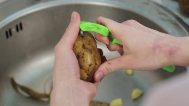 Handen schoon schil aardappel in gootsteen close-up — Stockvideo