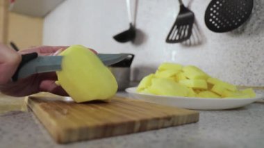 Eller tahtanın üzerinde patatesleri dilimlere ayırıyor. Yaklaş. 