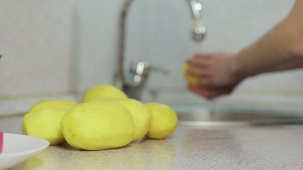 Geschälte Kartoffeln und Hände waschen Kartoffeln auf verschwommenem Hintergrund — Stockvideo