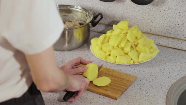 Las manos cortan las patatas en los trozos a la tabla de madera — Vídeos de Stock