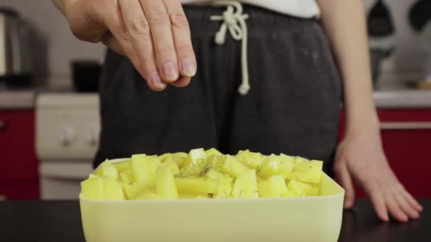 Niña espolvorea patatas sal en la cocina casera — Vídeos de Stock