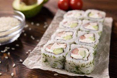 Avokado, domates, tavuk ve peynirli rulo siyah bir tahta üzerinde.