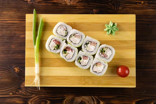 Salatalıklı suşi, tavuk, yeşil pırasa ve domates ahşap tahtada wasabi üst görüşlü.