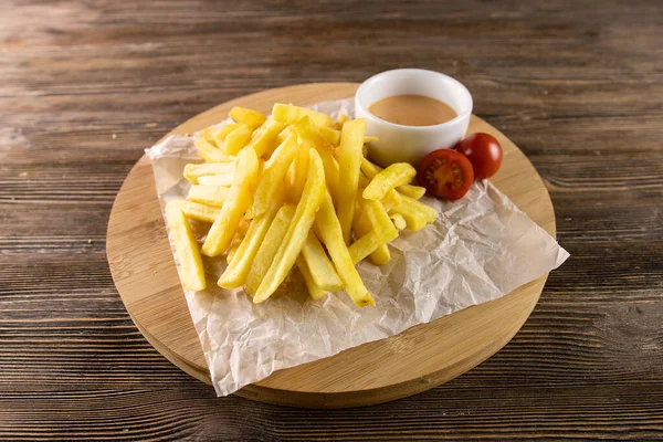 Kağıt üzerinde domates soslu kızarmış patates, yuvarlak masa ve masa. 