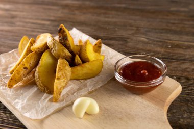 Domates, ketçap ve ahşap tahtada sarımsaklı patates.